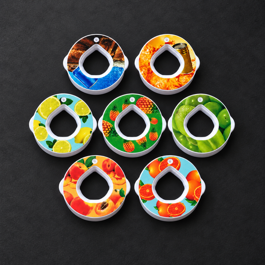 Les 7 pods aromatisés BatFit vus de dessus : cola, citron, pêche, Red Bull, orange, raisin, ananas